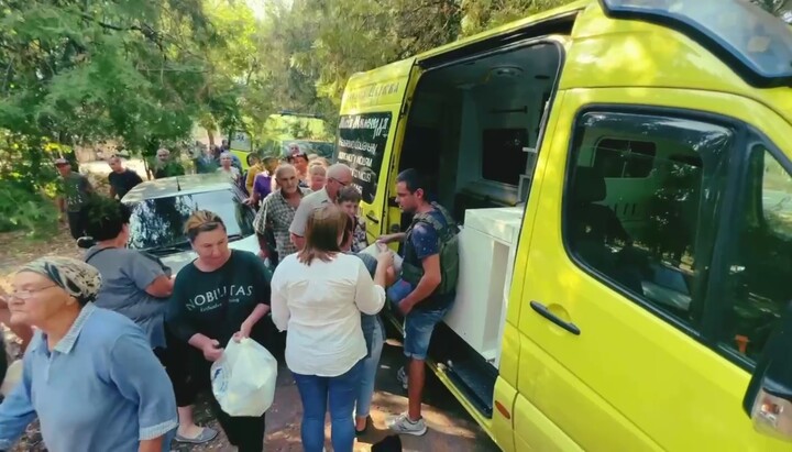 Представители Социального отдела УПЦ раздают гуманитарную помощь жителям поселка Садовое. Фото: скриншот видео Telegram-канала «Церква допомагає»